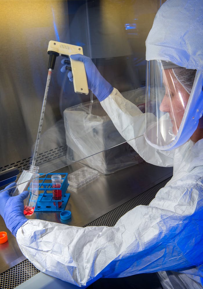 Scientist in protective gear performing lab experiment with precision and safety.